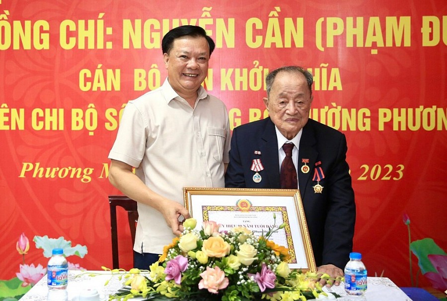 Bí thư Thành ủy Đinh Tiến Dũng trao Huy hiệu 80 năm tuổi Đảng và chúc mừng đồng chí Nguyễn Cần.