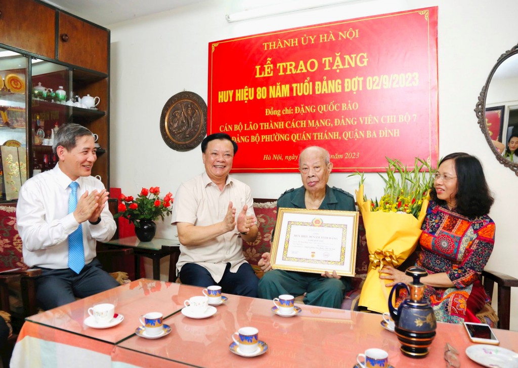 Bí thư Thành ủy Đinh Tiến Dũng trao Huy hiệu 80 năm tuổi Đảng và chúc mừng Thiếu tướng Đặng Quốc Bảo.