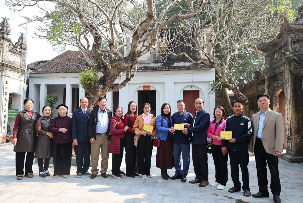 Các đồng chí lãnh đạo xã trao phiếu ghi nhận công đức của Ban quản lý Đền cho các gia đình