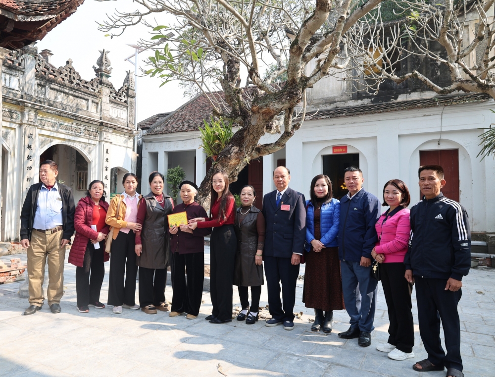 Các đồng chí lãnh đạo xã trao phiếu ghi nhận công đức của Ban quản lý Đền cho các gia đình