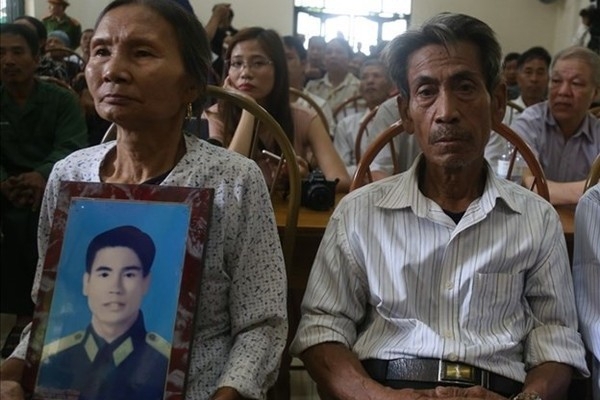 Vợ ông Trần Trung Thám ôm di ảnh của chồng ngồi cạnh ông Trần Ngọc Chinh.