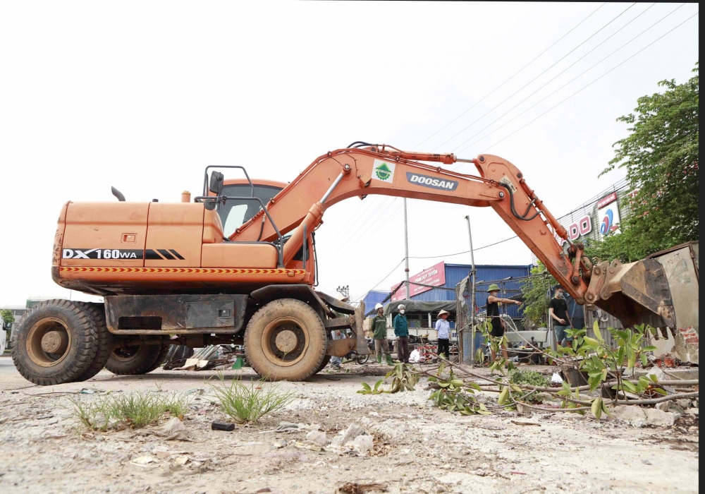 Lực lượng chức năng xử lý công trình vi phạm hành lang an toàn giao thông tại thị trấn Đạo Đức. Ảnh: Nguyễn Lượng