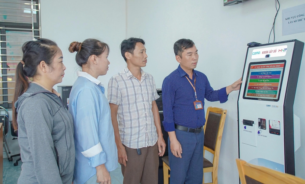 Cán bộ Trung tâm Phục vụ hành chính công xã Đại Đình hướng dẫn người dân lấy số thứ tự.