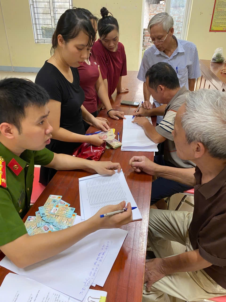 (Người dân tập trung tại Nhà văn hóa thôn để nhận quà. Không khí trật tự, phấn khởi và gắn bó, cho thấy sự chuẩn bị chu đáo của chính quyền và tinh thần đoàn kết của Nhân dân)