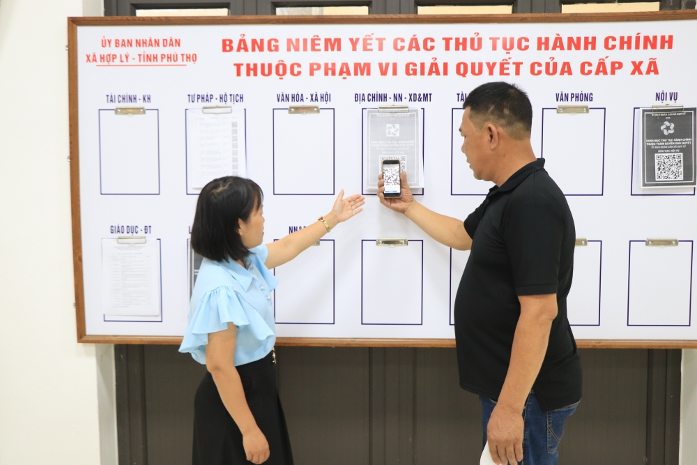 Cán bộ Trung tâm Phục vụ hành chính công xã Hợp Lý hướng dẫn người dân quét mã QR để tìm hiểu thủ tục hành chính trực tuyến.