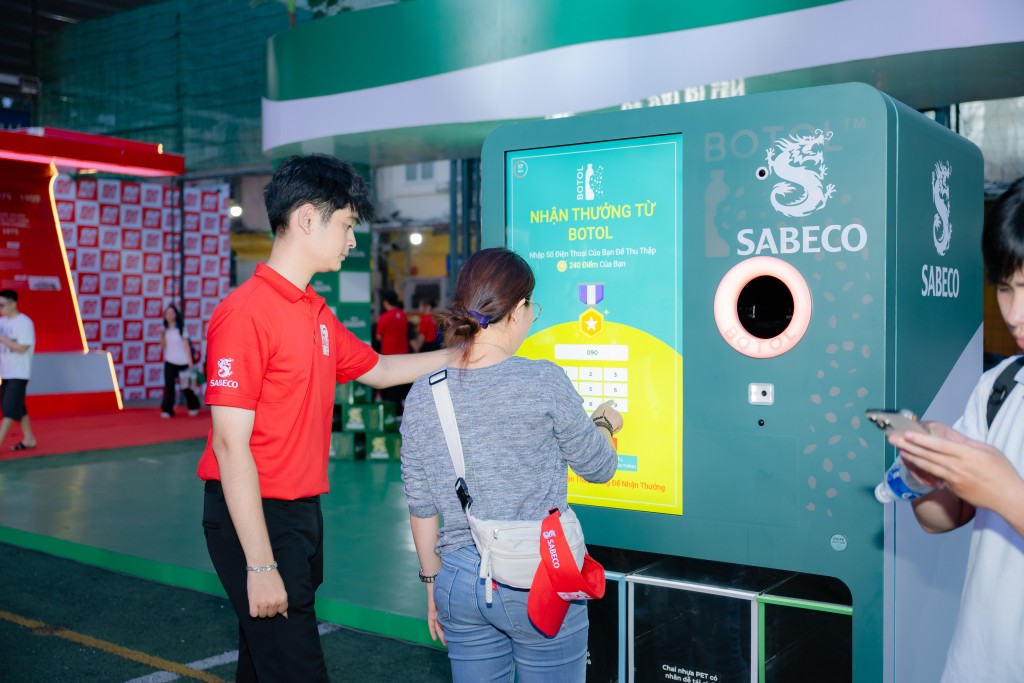 Người tham dự khám phá và tương tác với máy tái chế bao bì Người tham dự khám phá và tương tác với máy tái chế bao bì