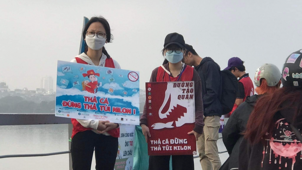 Tại Cầu Long Biên, ngay từ sáng sớm nhiều bạn trẻ đã có mặt với những biển bảng, khẩu hiệu tuyên truyền người dân thả cả chứ không thả túi nilon