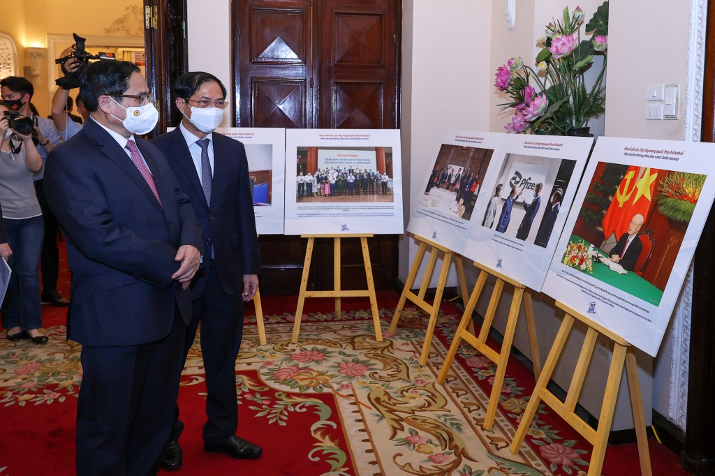 Thủ tướng Phạm Minh Chính tham quan trưng bày ảnh về hoạt động đối ngoại vaccine phòng, chống dịch COVID-19. (Ảnh: Dương Giang/TTXVN)