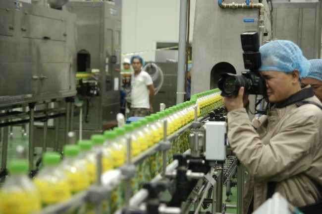Phóng viên báo chí tham quan dây chuyền sản xuất của một doanh nghiệp sản xuất nước giải khát