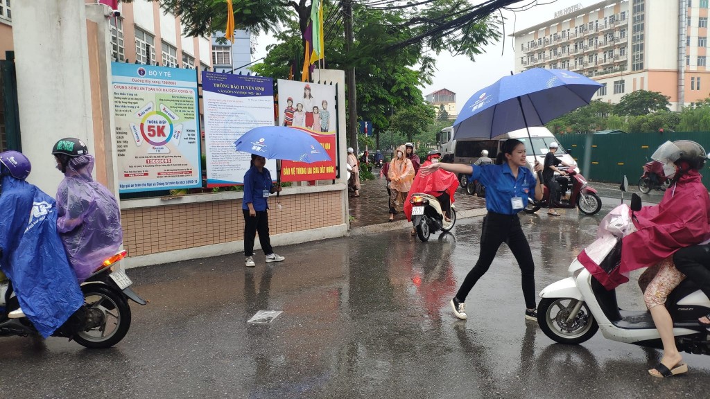 Tình nguyện viên  Thủ đô “đầu trần” hứng mưa, nhường  ô cho các thí sinh