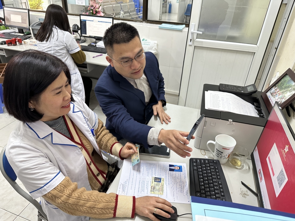 Cán bộ Trung tâm Y tế Yên Hoà (Quận Cầu Giấy, Hà Nội) hỗ trợ người dân thực hiện thao tác đổi bằng lái xe ô tô trên cổng dịch vụ công trực tuyến sau khi khám sức khoẻ hoàn thiện hồ sơ