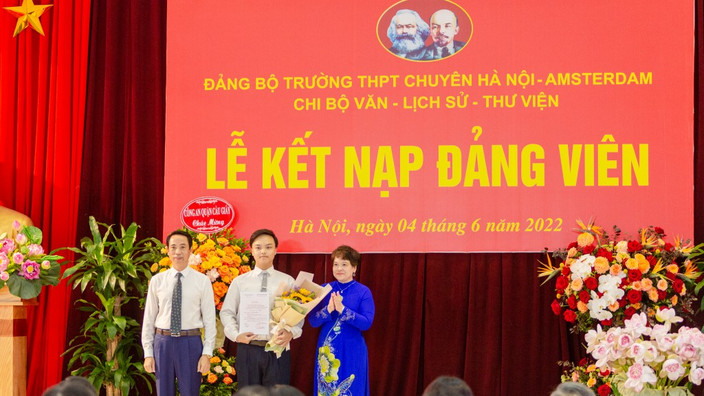 Nguyễn Hải Đăng (giữa) được thầy cô trao quyết định và tặng hoa chúc mừng tại lễ kết nạp Đảng