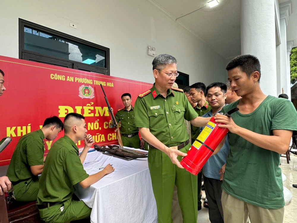 Đại tá Thành Kiên Trung - Trưởng Công an quận Cầu Giấy trao bình chữa cháy cho người dân đến điểm thu đổi vũ khí, vật liệu nổ phường Trung Hoà