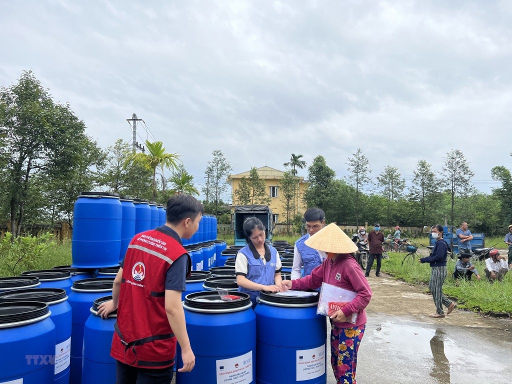 Hỗ trợ thùng nhựa cho các gia đình có nguy cơ chịu ngập lụt do mưa bão ở Thừa Thiên-Huế. (Ảnh: TTXVN)