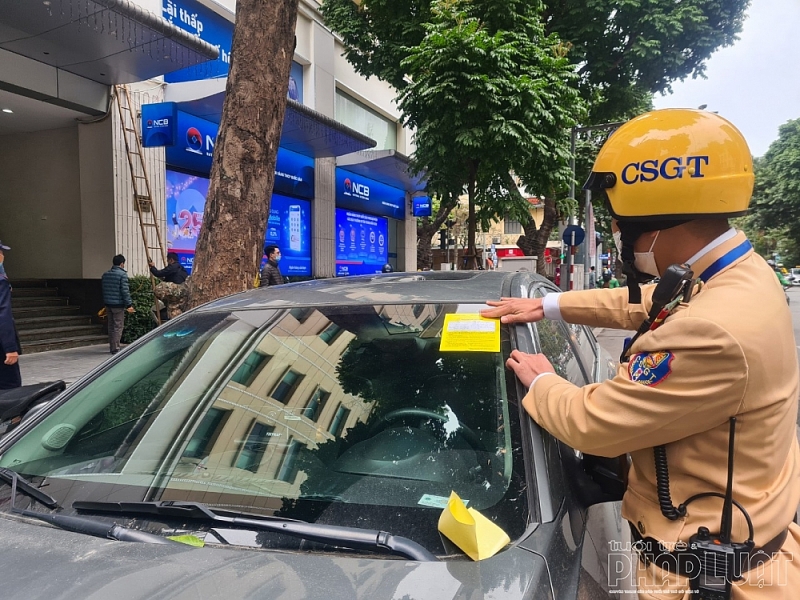 Cán bộ Đội CSGT số 1 dán thông báo vi phạm lên kính xe