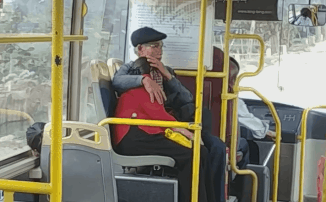 Cụ ông che chở cụ bà trên xe buýt