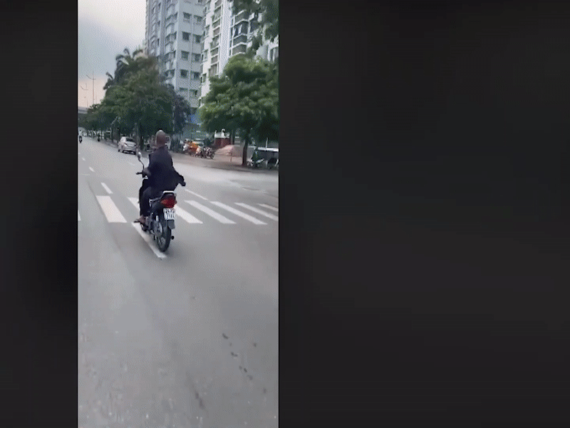 Cụ ông mở nhạc, nằm lên yên điều khiển xe máy trên phố Hà Nội