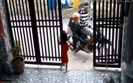 Người phụ nữ vào trong sân giật điện thoại trên tay bé gái