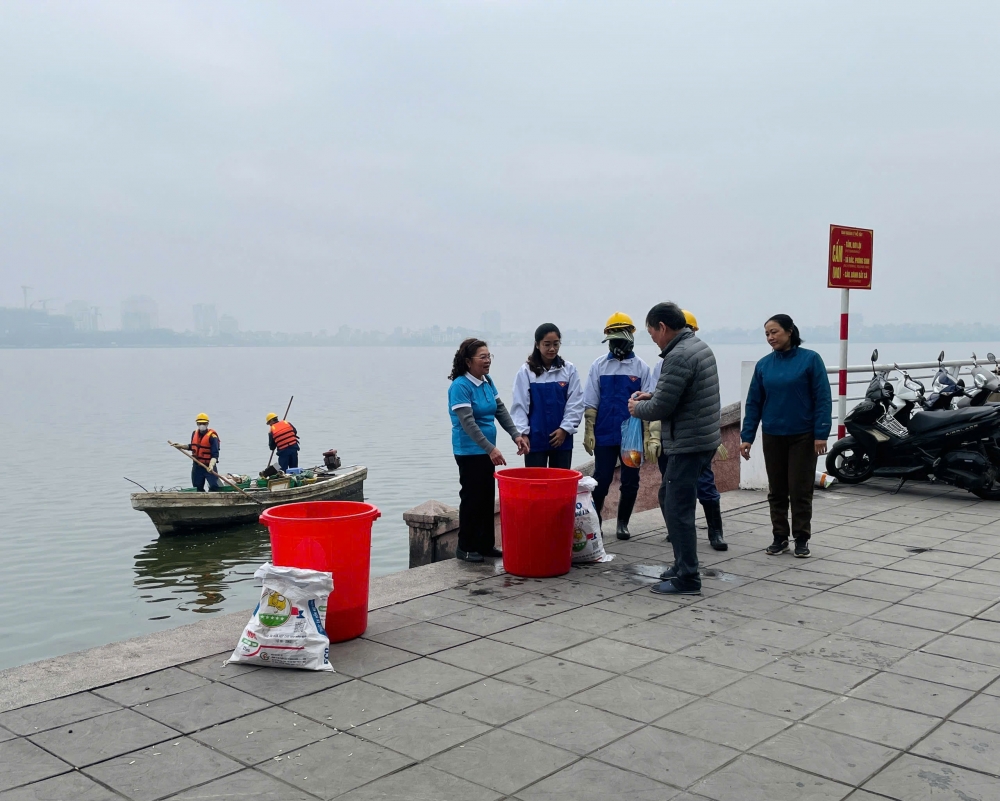 Công nhân thoát nước Hà Nội hướng dẫn, giúp đỡ người dân thả cá đúng quy định