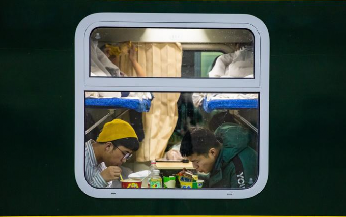 2 nam thanh niên Trung Quốc ăn lót dạ mỳ trên chuyến tàu hồi hương. (Ảnh: SBS)