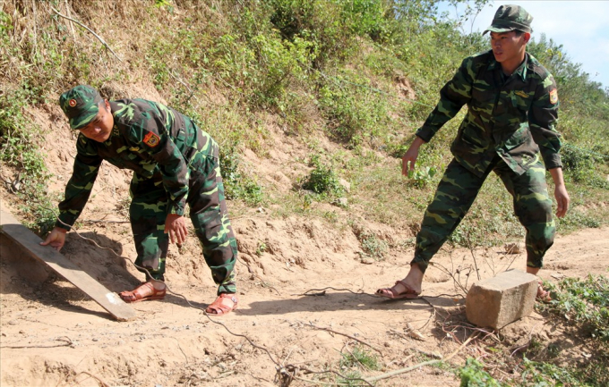 Theo thượng úy Lê Đăng Thức (bìa phải ảnh) - Đội trưởng Đội trinh sát Đồn Biên phòng Cửa khẩu Quốc tế Lao Bảo, việc vận chuyển hàng lậu từ sông Sê Pôn vào khu dân cư diễn ra vào lúc nửa đêm. Ngoài việc chặn đá, các đối tượng còn giăng dây dọc tuyến đường. Ảnh: Hưng Thơ.