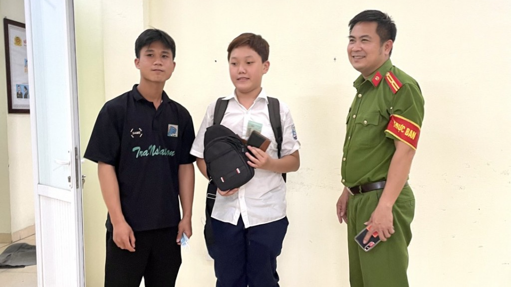 Em Bùi Đức Quang (giữa) cùng cán bộ Công an phường trao lại tài sản cho người đánh rơi tại trụ sở Công an phường Bồ Đề