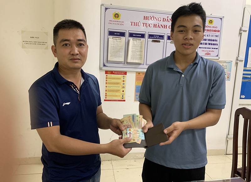 Đại úy Nguyễn Duy Điệp, cán bộ Đội CSGT số 8 (bên trái) trao trả chiếc ví có thẻ CCCD cùng số tiền hơn 2 triệu đồng cho nam sinh Nguyễn Long Vũ