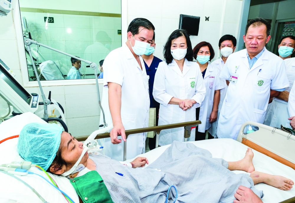 Bộ trưởng Đào Hồng Lan (đứng giữa) thăm bệnh nhân đang điều trị tại Bệnh viện Bạch Mai. Ảnh: Trần Minh