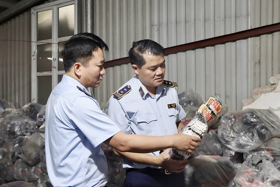 Lực lượng chức năng kiểm tra lô tất giả nhãn hiệu tại Công ty TNHH Sản xuất và Kinh doanh Sơn Vân Nam (huyện Hoài Đức).