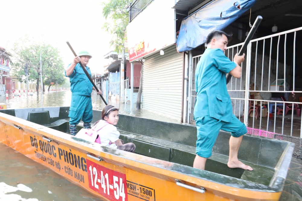 Lực lượng cứu hộ của xã Tiến Thắng đưa học sinh vượt mưa lũ đến trường