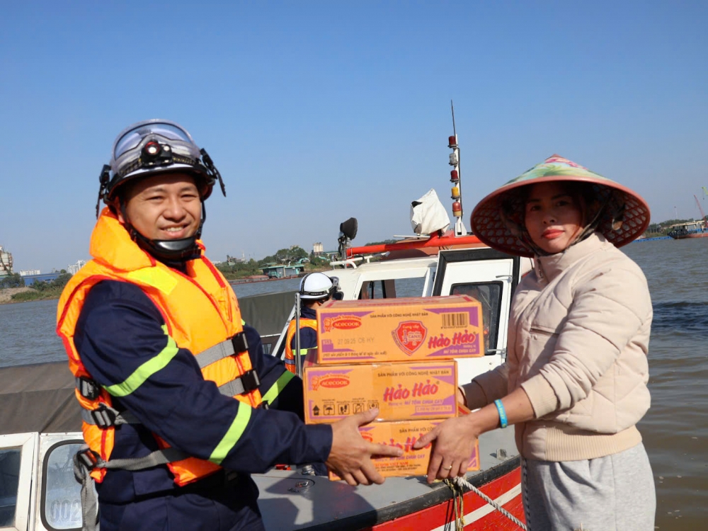 Đại úy Lê Văn Linh, cán bộ Đội Cảnh sát PCCC và CNCH trên sông trao quà đến các hộ dân của xóm chài.